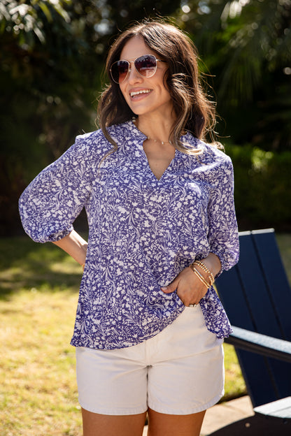 Woman wearing a purple floral blouse and white shorts outdoors