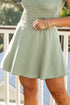Person wearing a light green strapless dress on a balcony with blurred background