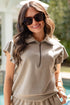 Woman in beige outfit with sunglasses by a pool