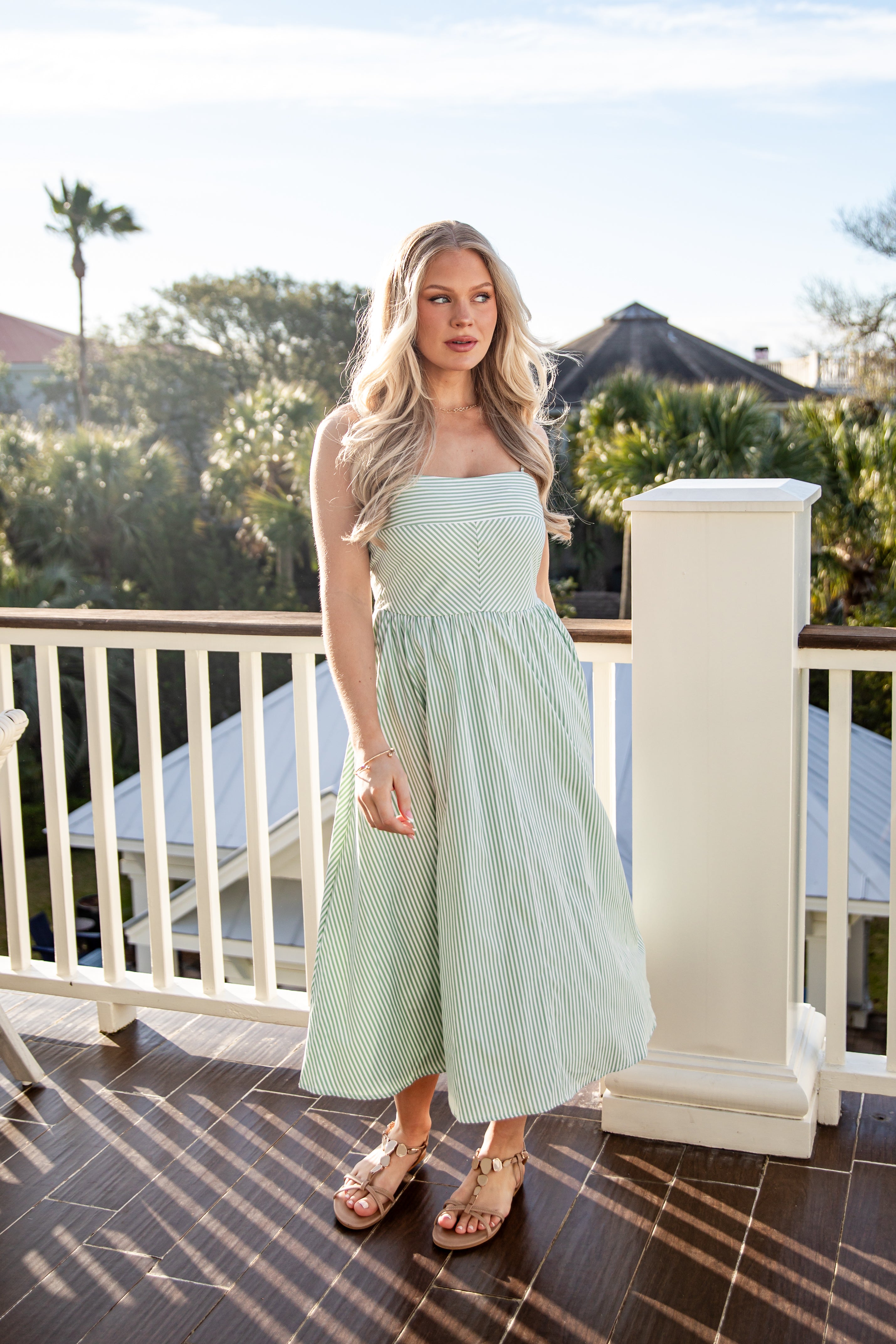 Woman in a light green dress standing on a balcony with a scenic background
