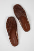 A pair of brown woven leather mule sandals with a square toe, displayed on a light gray background. The brand name &