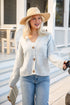 Woman wearing a light blue cardigan, jeans, and a straw hat outdoors.