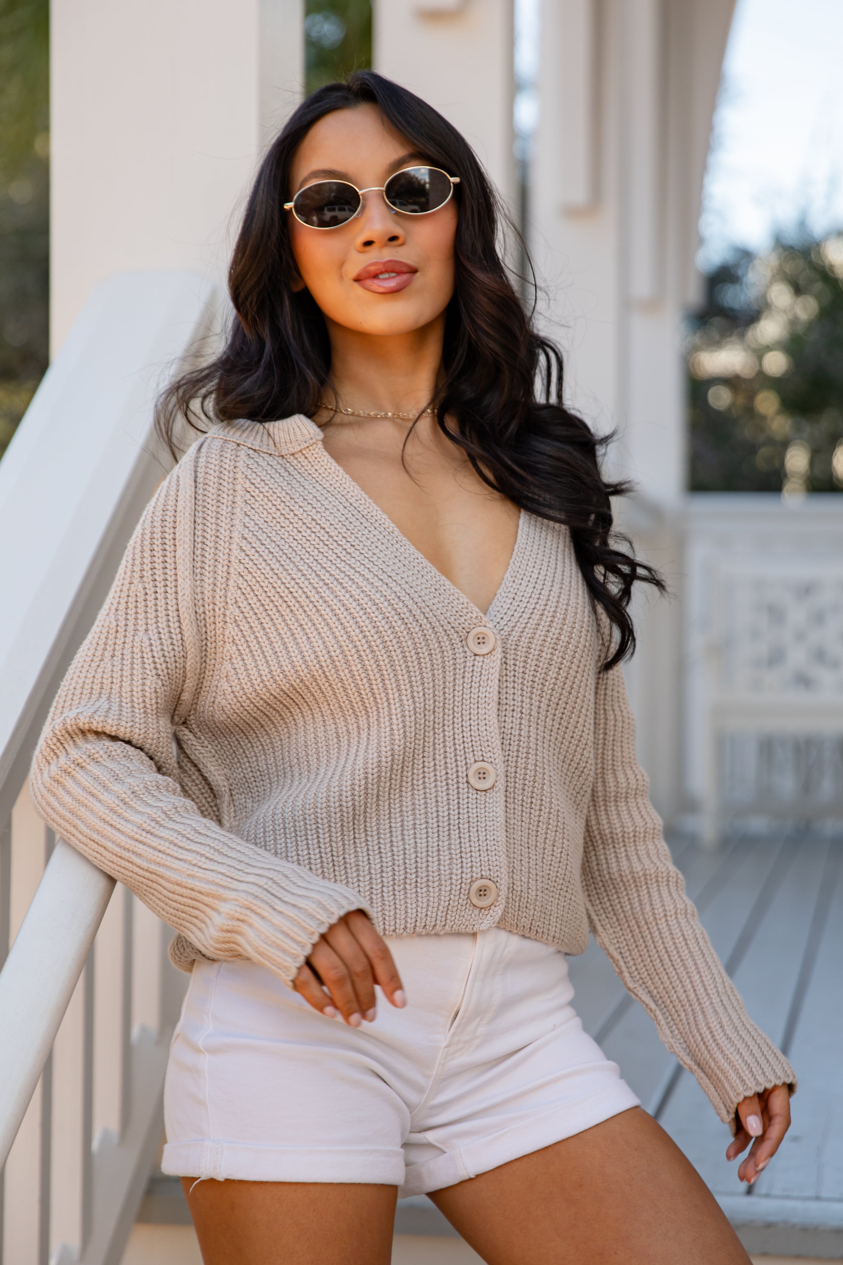 Woman wearing a beige cardigan and white shorts outdoors