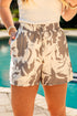 Person wearing floral tropical shorts by a poolside