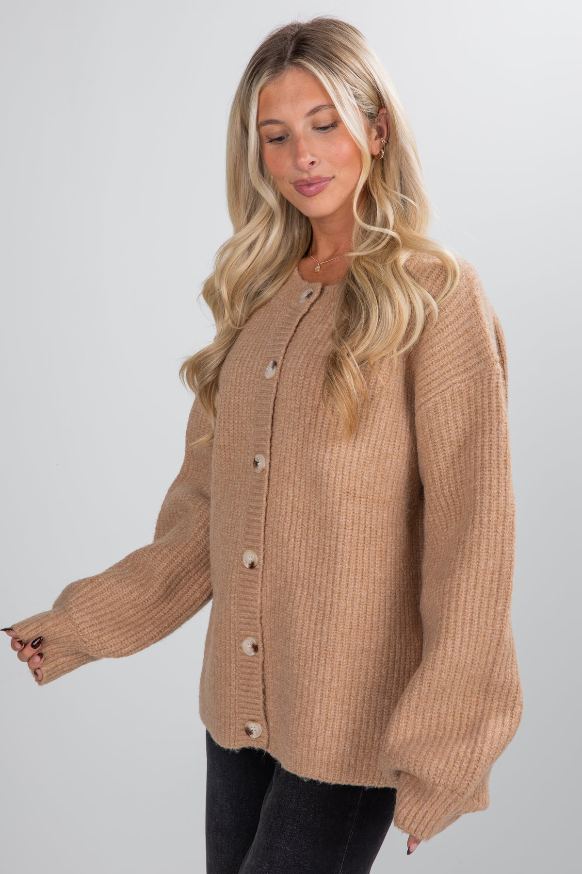 Woman wearing a beige cardigan against a white background