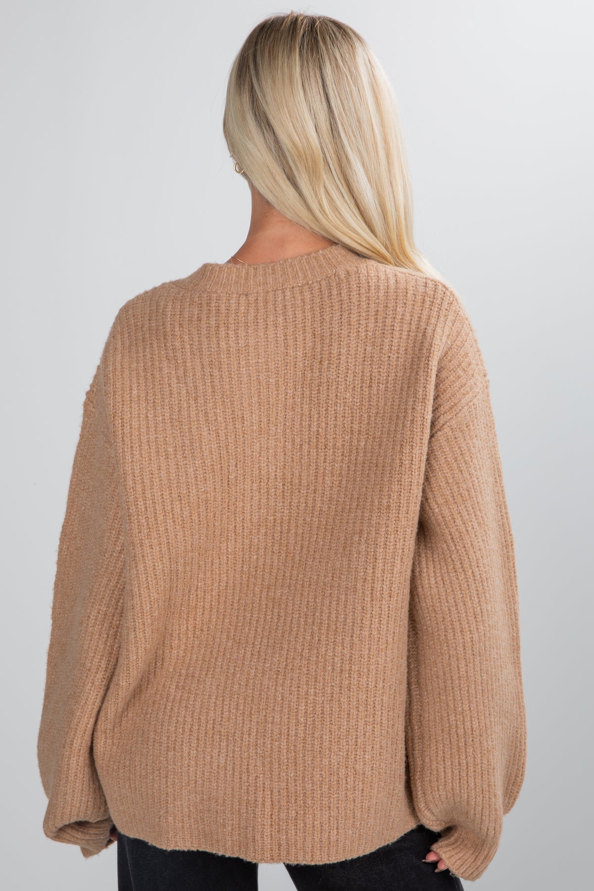 Person wearing a brown sweater on a plain background