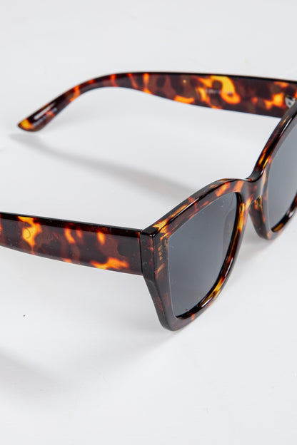 Sunglasses with tortoiseshell frame and dark lenses on a white background