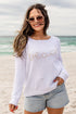 Woman wearing a white sweater with &