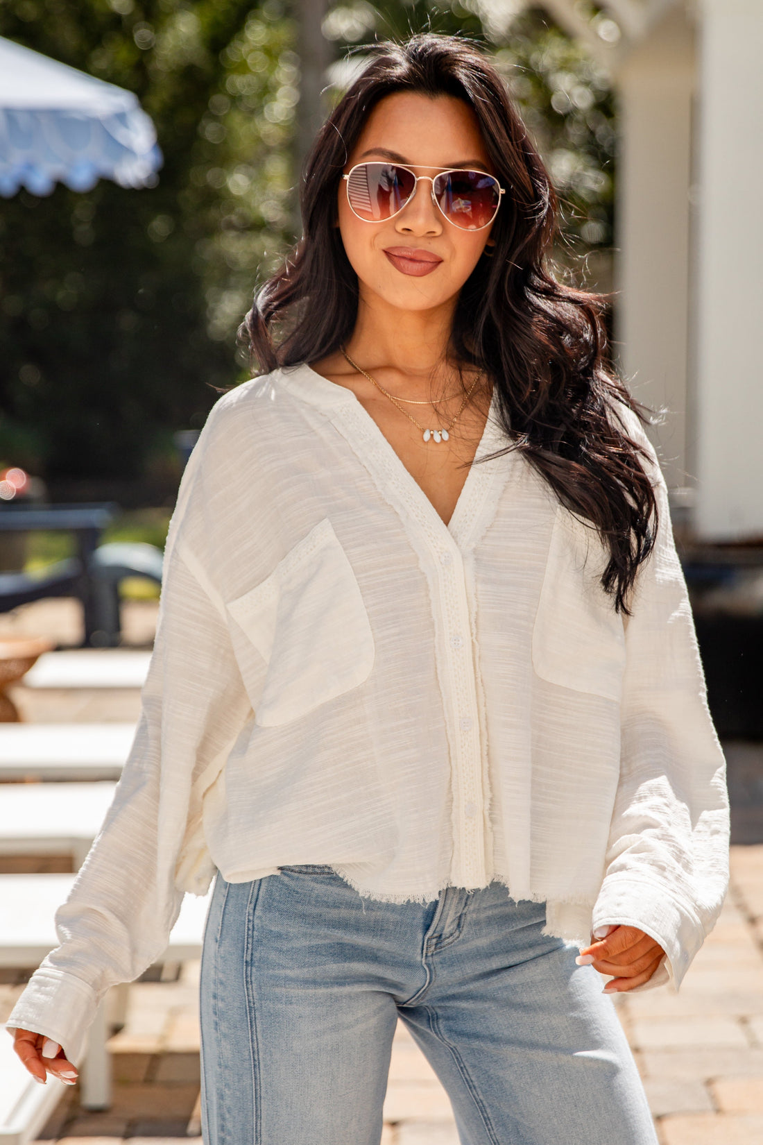 Woman wearing a white blouse and light blue jeans outdoors.