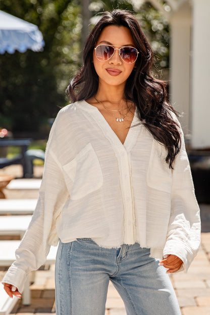 Woman wearing a white blouse and light blue jeans outdoors.