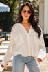 Woman wearing a white blouse and light blue jeans outdoors.