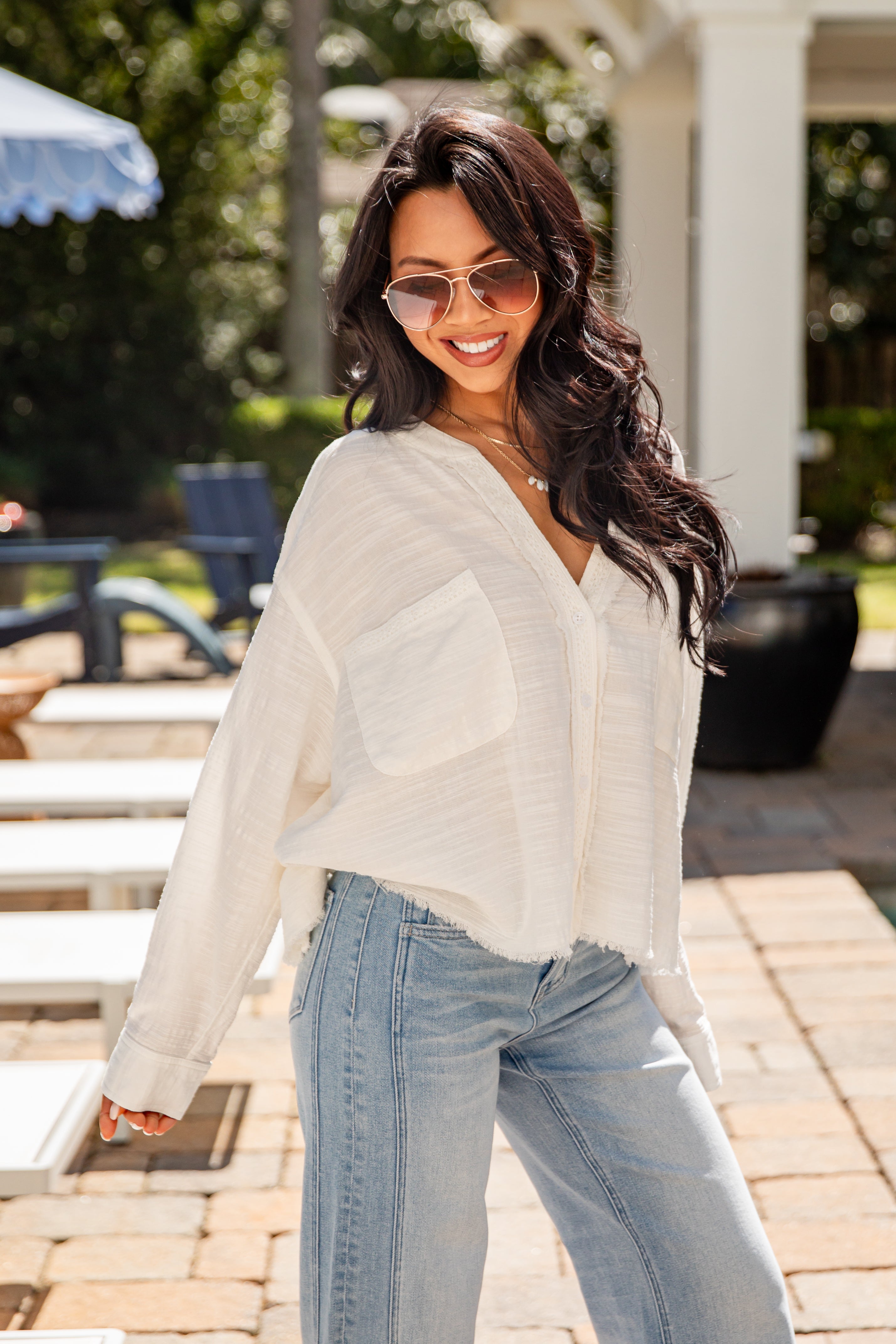 Woman wearing a white blouse and light blue jeans outdoors.