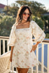 Woman wearing a floral dress on a balcony with greenery in the background