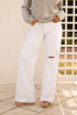 Person wearing white flared jeans and a gray sweater against a neutral background