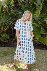 Woman wearing a floral dress standing in front of palm trees