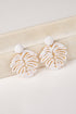White earrings with gold accents on a light wooden surface