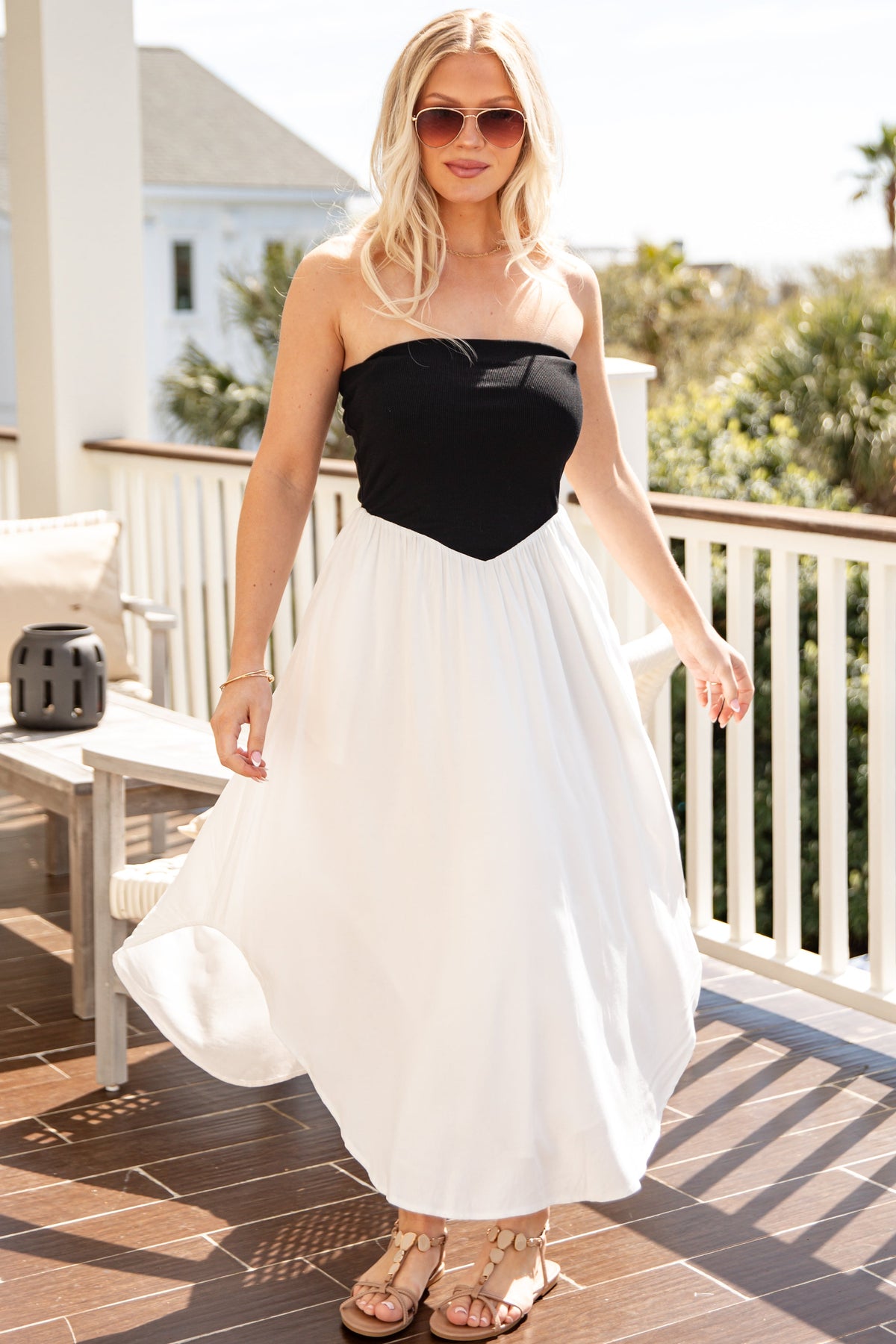 Woman in a black and white dress standing on a patio with a scenic background