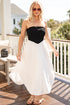 Woman in a black and white dress standing on a patio with a scenic background