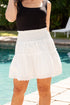Person wearing a black top and white skirt by a pool