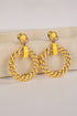 Yellow hoop earrings with intricate designs on a beige surface